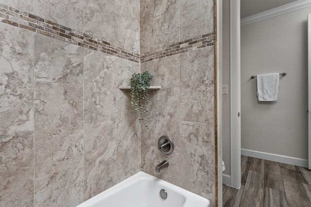 bathroom featuring crown molding, wood finished floors, shower / washtub combination, and baseboards