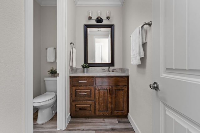 bathroom with wood finished floors, ornamental molding, vanity, toilet, and baseboards