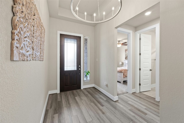 foyer featuring light wood-type flooring, baseboards, a chandelier, recessed lighting, and a textured wall
