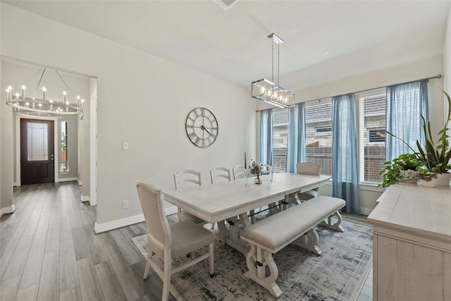 dining room with a chandelier, baseboards, and light wood-style floors