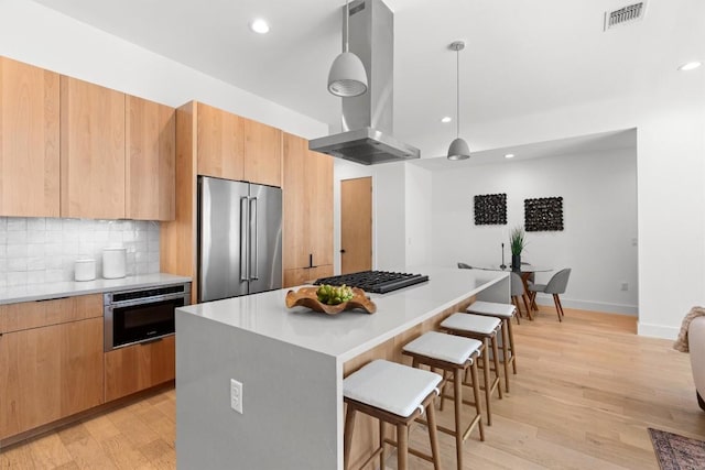 2003 Karen Ave Unit A, Austin, TX 78757 - kitchen with stainless steel appliances, island range hood, a breakfast bar area, a kitchen island, and light wood finished floors
