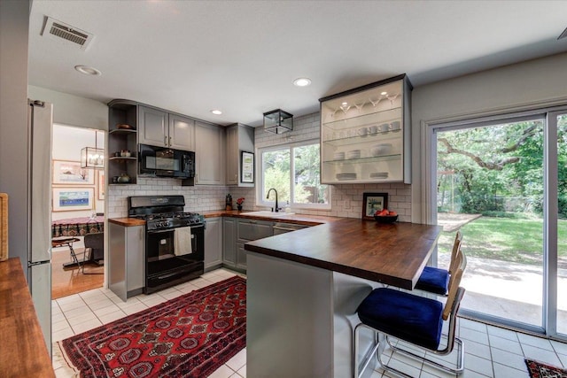 6018 Abilene Trl, Austin, TX 78749 - kitchen featuring black appliances, gray cabinets, open shelves, decorative backsplash, and a peninsula
