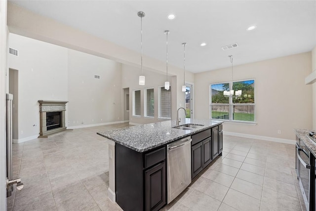 2713 Margarita Ct, Round Rock, TX 78665 - kitchen with stainless steel appliances, a sink, light tile patterned floors, light stone counters, and a glass covered fireplace