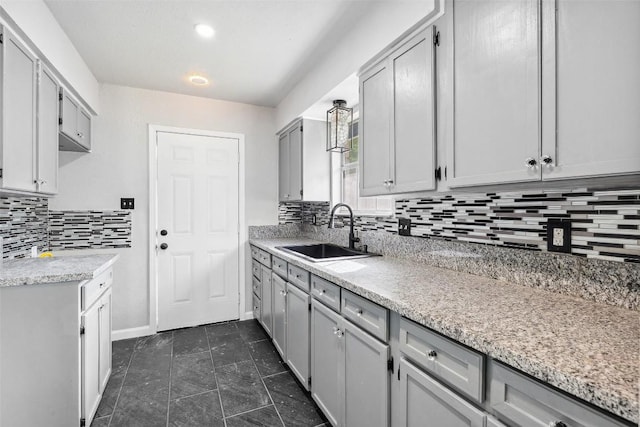 7000 Carwill Dr, Austin, TX 78724 - kitchen featuring a sink, gray cabinetry, decorative backsplash, baseboards, and dark tile patterned floors