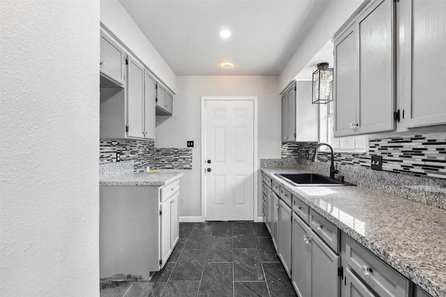 7000 Carwill Dr, Austin, TX 78724 - kitchen with a sink, gray cabinets, backsplash, dark tile patterned flooring, and baseboards