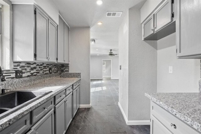 7000 Carwill Dr, Austin, TX 78724 - kitchen with ceiling fan, a sink, gray cabinets, baseboards, and a textured wall