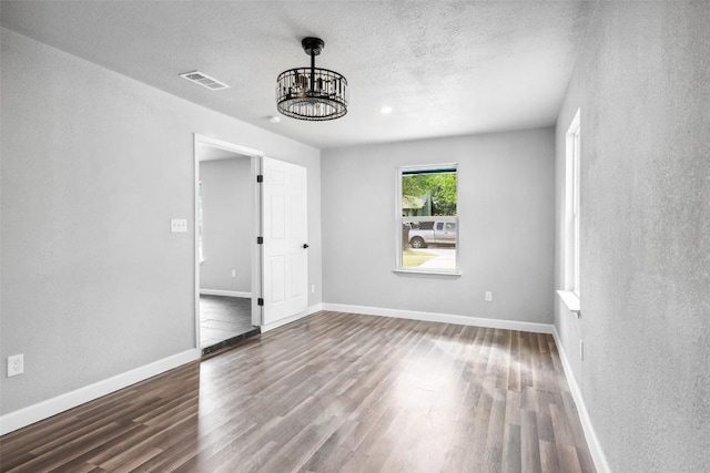 7000 Carwill Dr, Austin, TX 78724 - spare room with wood finished floors, a chandelier, baseboards, and a textured ceiling