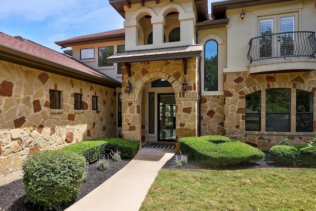 doorway to property featuring stone siding, a balcony, a standing seam roof, and metal roof