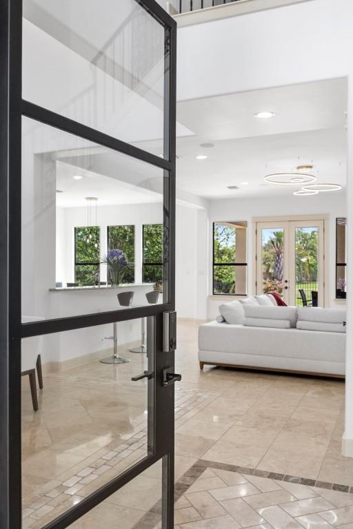living room with a chandelier, recessed lighting, french doors, and inlaid floor details