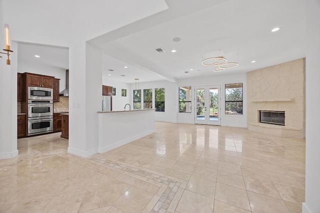 unfurnished living room with recessed lighting, baseboards, light marble finish flooring, and a fireplace