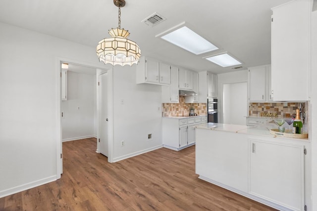 507 Canyon Wren Dr, Buda, TX 78610 - kitchen featuring under cabinet range hood, double oven, tasteful backsplash, a peninsula, and light countertops
