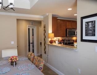 834 Salado Creek Ln, Georgetown, TX 78633 - kitchen featuring stainless steel microwave, brown cabinets, ornamental molding, recessed lighting, and range