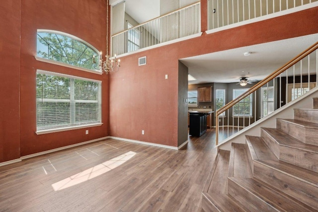 14104 Ballycastle Trl, Austin, TX 78717 - unfurnished living room with a towering ceiling, stairway, wood finished floors, and a ceiling fan