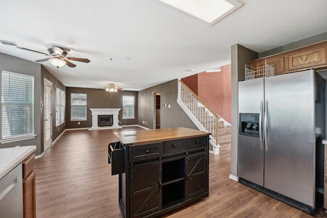 14104 Ballycastle Trl, Austin, TX 78717 - kitchen with appliances with stainless steel finishes, a ceiling fan, wood finished floors, a fireplace with raised hearth, and open floor plan