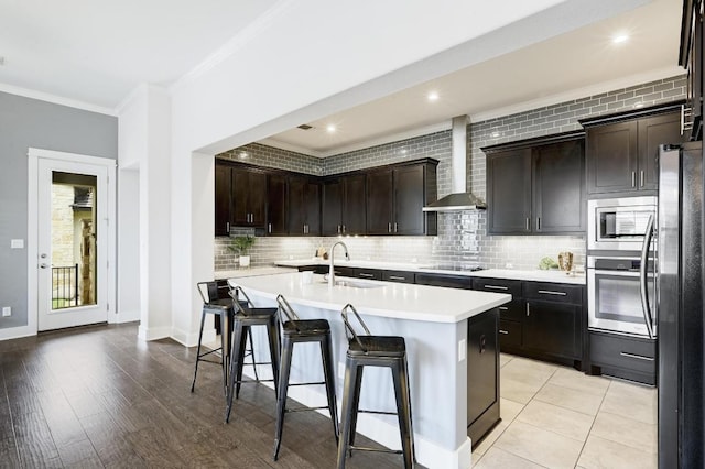 5303 Patagonia Pass, Austin, TX 78738 - kitchen featuring a sink, wall chimney exhaust hood, stainless steel appliances, light countertops, and a center island with sink