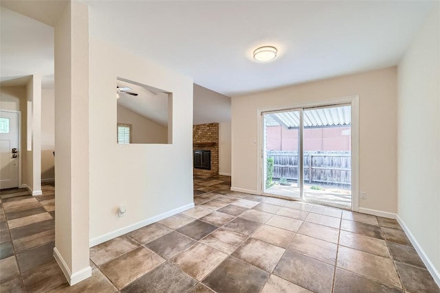 empty room featuring a fireplace, baseboards, a ceiling fan, and vaulted ceiling