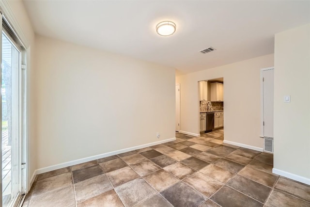 spare room with baseboards, a sink, and stone finish flooring