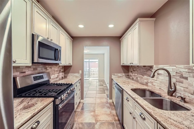 kitchen featuring appliances with stainless steel finishes, a sink, backsplash, recessed lighting, and light stone counters