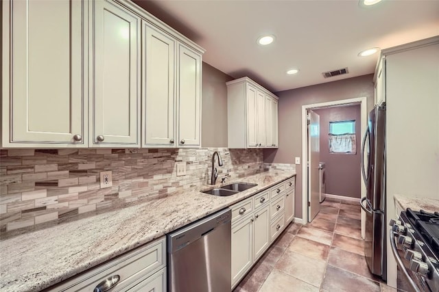 kitchen with appliances with stainless steel finishes, a sink, recessed lighting, backsplash, and light stone countertops