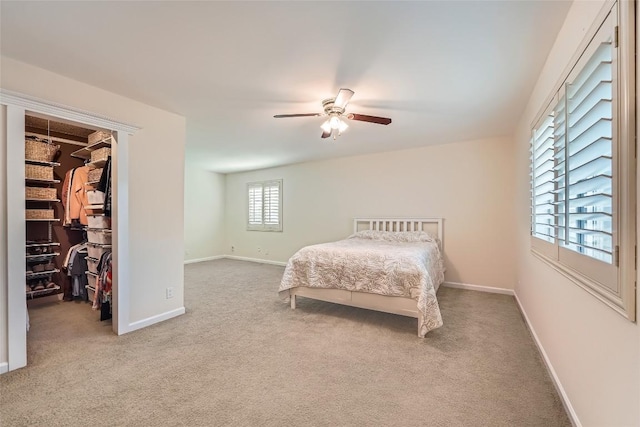 carpeted bedroom with a spacious closet, baseboards, ceiling fan, and a closet