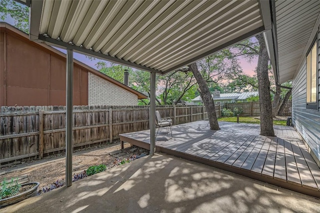 patio terrace at dusk with a fenced backyard and a wooden deck