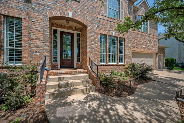 property entrance with concrete driveway, a garage, and brick siding