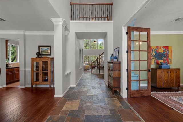 foyer entrance with plenty of natural light, ornamental molding, baseboards, stairway, and a high ceiling