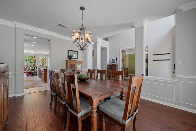 dining area with dark wood finished floors, a chandelier, ornamental molding, and ornate columns
