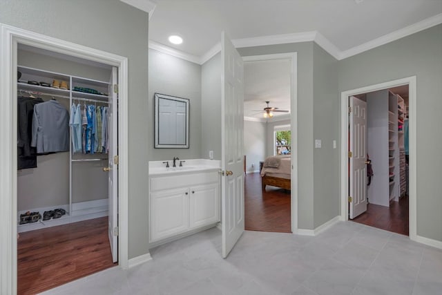 bathroom with ornamental molding, ceiling fan, vanity, baseboards, and ensuite bathroom