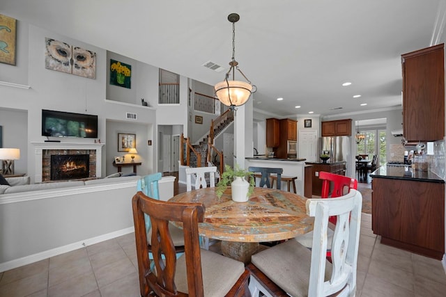 dining space featuring light tile patterned flooring, a stone fireplace, stairs, recessed lighting, and baseboards