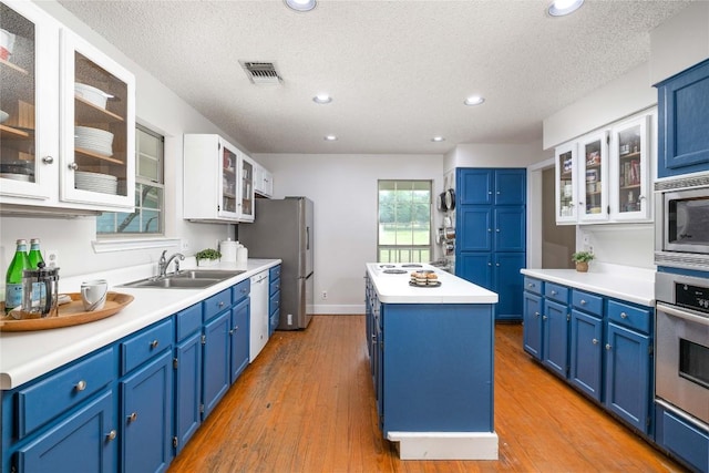 28920 Country Dr, New Braunfels, TX 78132 - kitchen with stainless steel appliances, blue cabinetry, a sink, a kitchen island, and a textured ceiling