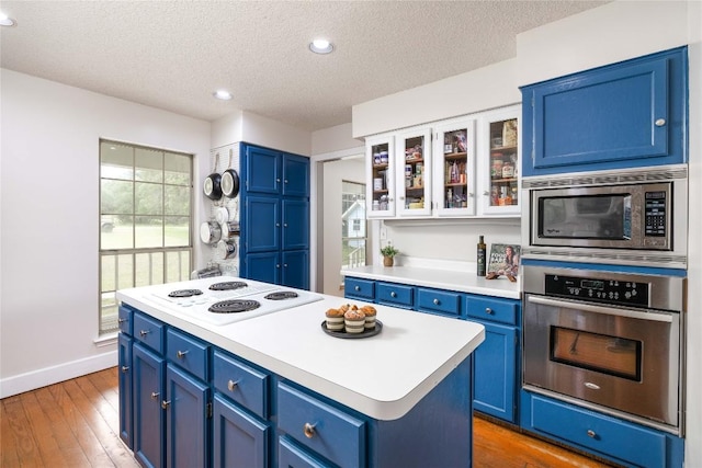28920 Country Dr, New Braunfels, TX 78132 - kitchen featuring stainless steel appliances, blue cabinets, a textured ceiling, light countertops, and baseboards