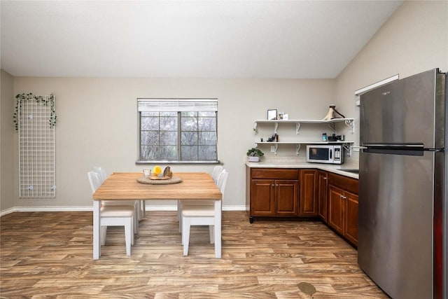28920 Country Dr, New Braunfels, TX 78132 - kitchen with appliances with stainless steel finishes, wood finished floors, open shelves, light countertops, and baseboards