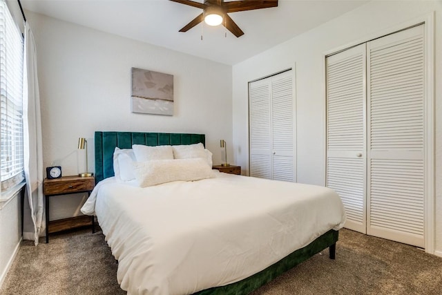 carpeted bedroom with two closets, baseboards, and ceiling fan