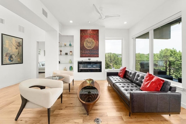 5728 Misty Hill Cv, Austin, TX 78759 - living room featuring plenty of natural light, light wood-type flooring, recessed lighting, a glass covered fireplace, and a ceiling fan