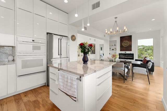 5728 Misty Hill Cv, Austin, TX 78759 - kitchen with modern cabinets, double oven, white cabinets, light wood-style floors, and freestanding refrigerator