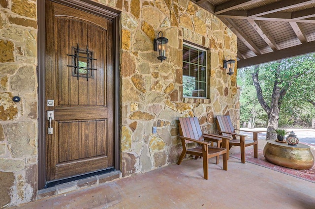 view of exterior entry featuring stone siding and a porch
