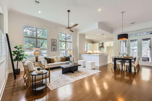living area featuring dark wood-type flooring, a ceiling fan, baseboards, crown molding, and recessed lighting