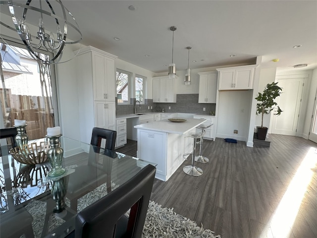 2111 Prather Ln Unit 1, Austin, TX 78704 - kitchen with a chandelier, a kitchen island, white cabinetry, tasteful backsplash, and dark wood-style flooring