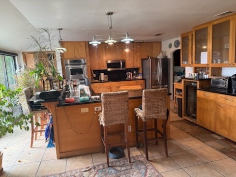 909 Redbud Trl, West Lake Hills, TX 78746 - kitchen featuring stainless steel appliances, a center island, light tile patterned flooring, dark countertops, and a breakfast bar area