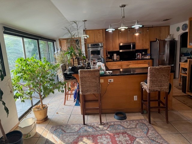 909 Redbud Trl, West Lake Hills, TX 78746 - kitchen with stainless steel appliances, light tile patterned floors, dark countertops, and brown cabinetry
