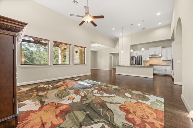 2761 Fishing Hole Cv, Leander, TX 78641 - living room featuring a ceiling fan, a high ceiling, dark wood-style flooring, arched walkways, and recessed lighting