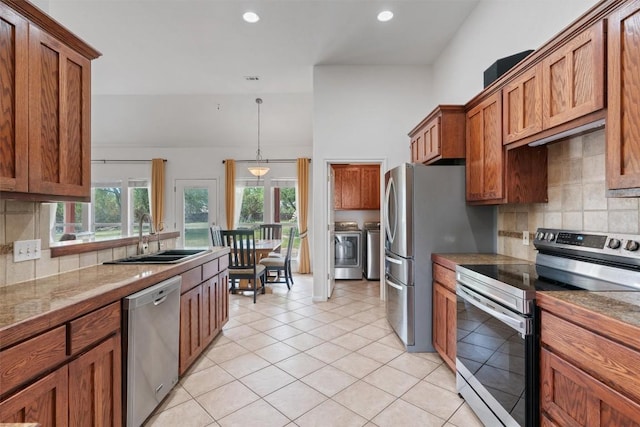 920 Barton Creek Dr, Dripping Springs, TX 78620 - kitchen featuring stainless steel appliances, a sink, independent washer and dryer, brown cabinetry, and decorative backsplash