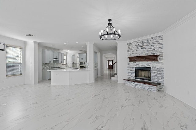 unfurnished living room featuring crown molding, light marble finish flooring, a fireplace, a chandelier, and recessed lighting