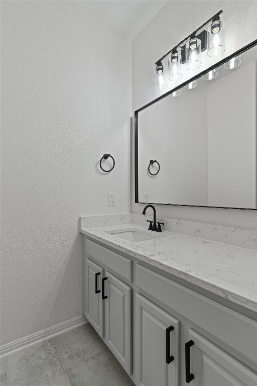 bathroom featuring baseboards, vanity, and a textured wall