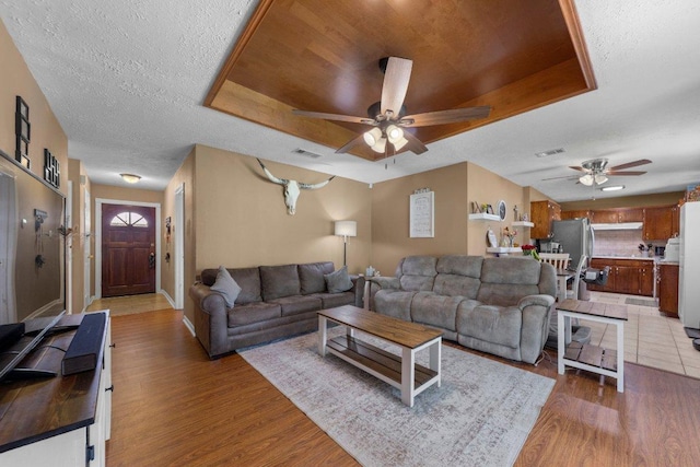 1611 Velma Ave, Copperas Cove, TX 76522 - living area featuring ceiling fan, a tray ceiling, light wood finished floors, baseboards, and a textured ceiling