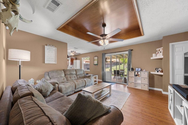 1611 Velma Ave, Copperas Cove, TX 76522 - living area with ceiling fan, a textured ceiling, light wood-type flooring, baseboards, and a raised ceiling