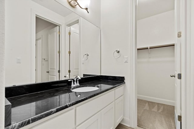 bathroom featuring baseboards, vanity, and a walk in closet
