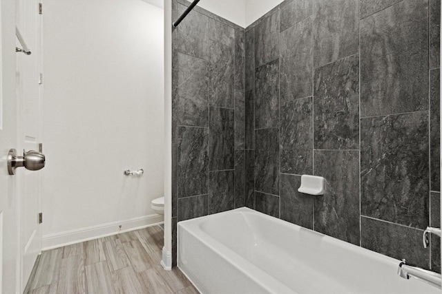 bathroom with toilet, baseboards, and  shower combination