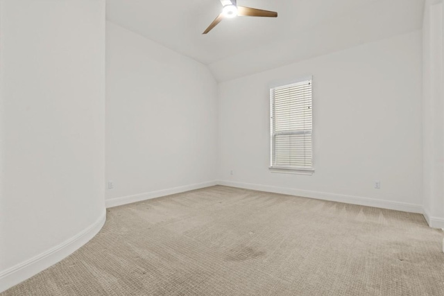 empty room with light colored carpet, ceiling fan, lofted ceiling, and baseboards